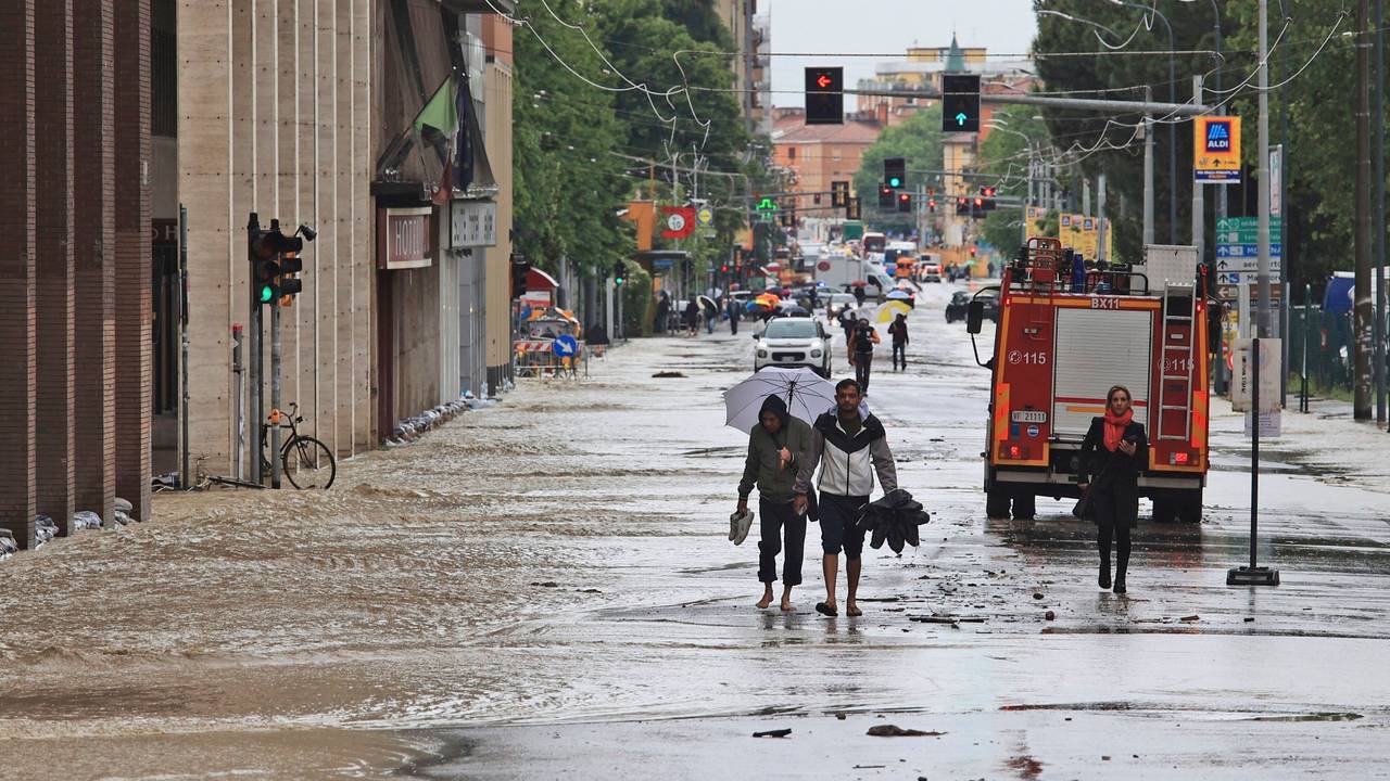 Menschen bahnen sich am 17. Mai ihren Weg durch eine überflutete Straße in Bologna.