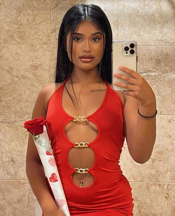 TikTokerin und OnlyFans-Model Tia Kabir in einem roten Kleid und einer roten Rose.