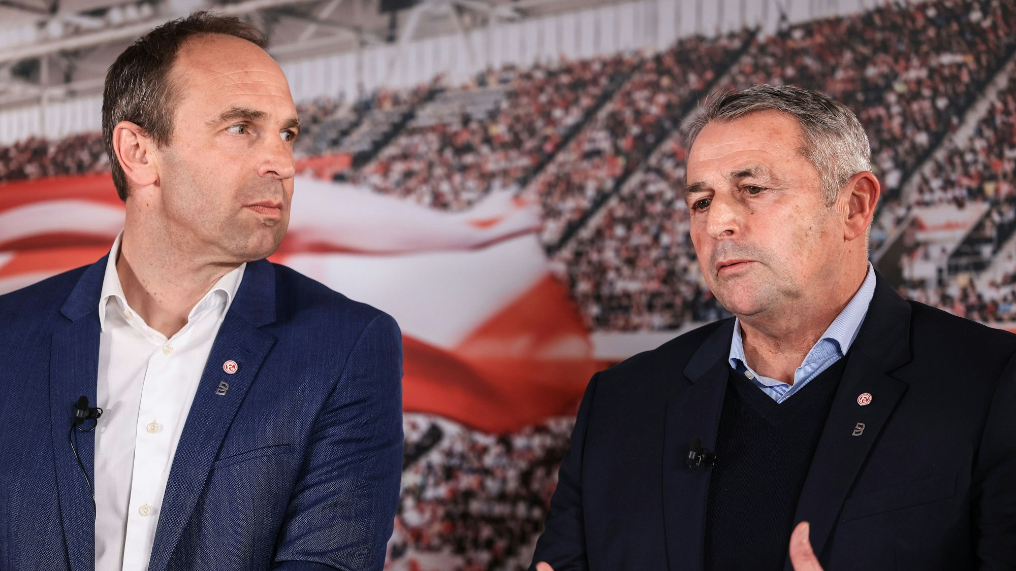 Alexander Jobst, Vorstandsvorsitzender von Fortuna Düsseldorf, und Klaus Allofs, Vorstandsmitglied, stehen gemeinsam nebeneinander auf dem Podium.