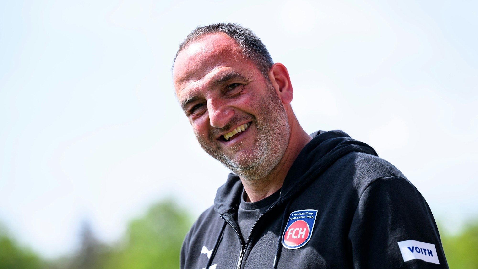 Heidenheim-Trainer Frank Schmidt lacht in die Kamera.