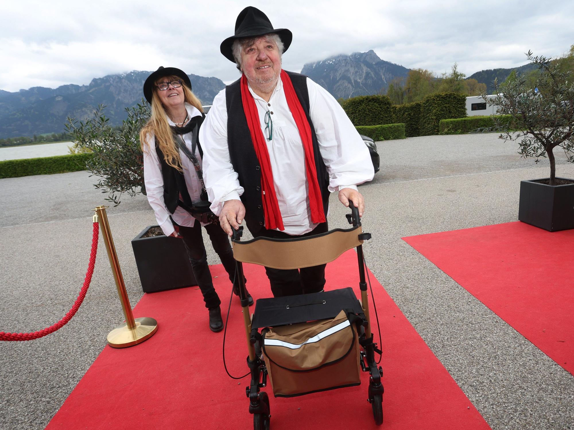 Michael Schanze kommt mit einem Rollator auf den roten Teppich.