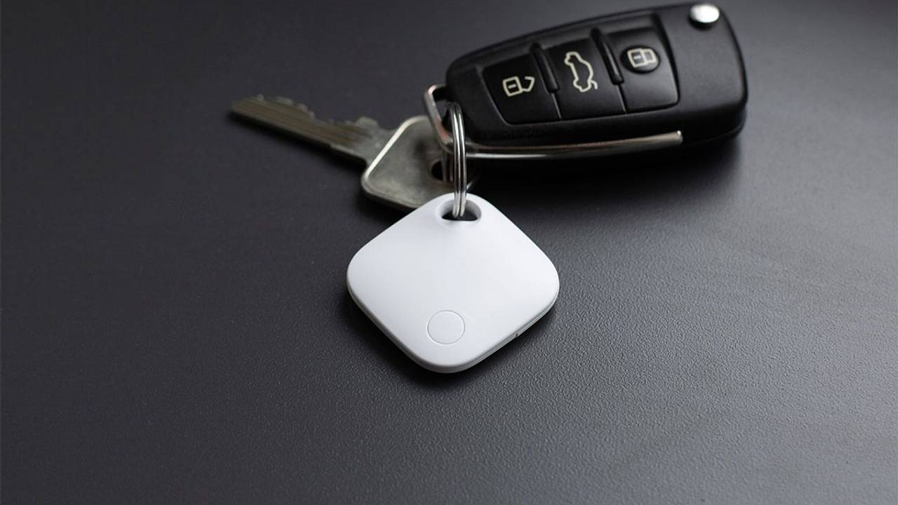 Aldi Smart Tag in Weiß hängt am Autoschlüssel und liegt auf dem Tisch.
