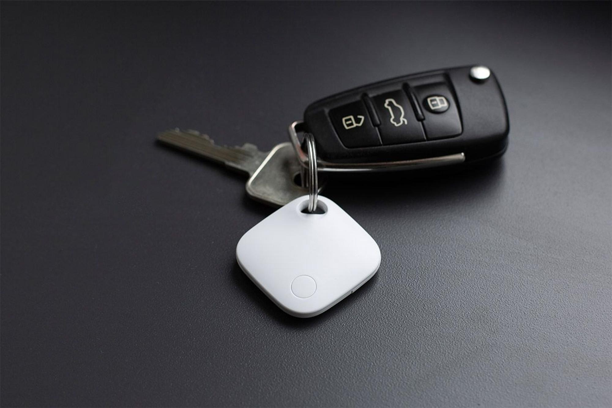 Aldi Smart Tag in Weiß hängt am Autoschlüssel und liegt auf dem Tisch.