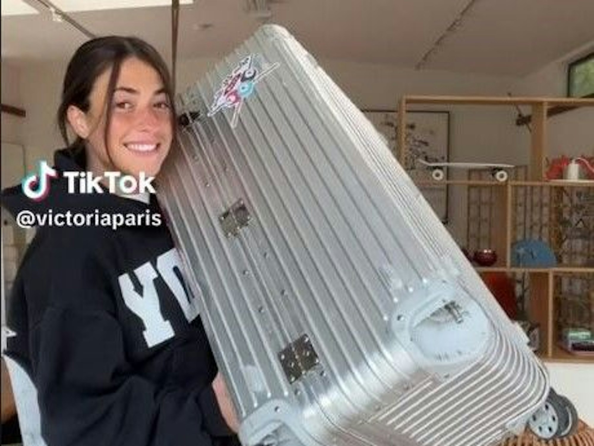 Eine Frau hält einen silbernen Koffer vor ihren Körper.