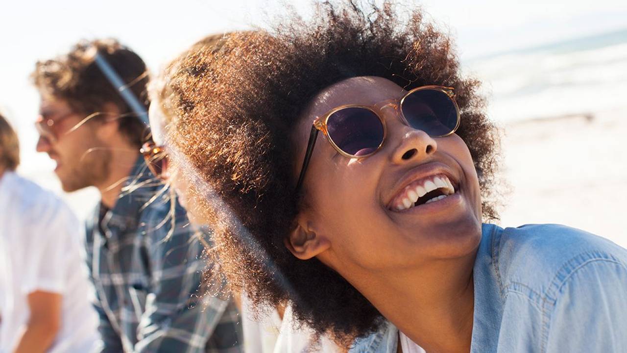Frau mit Sonnenbrille lacht am Meer