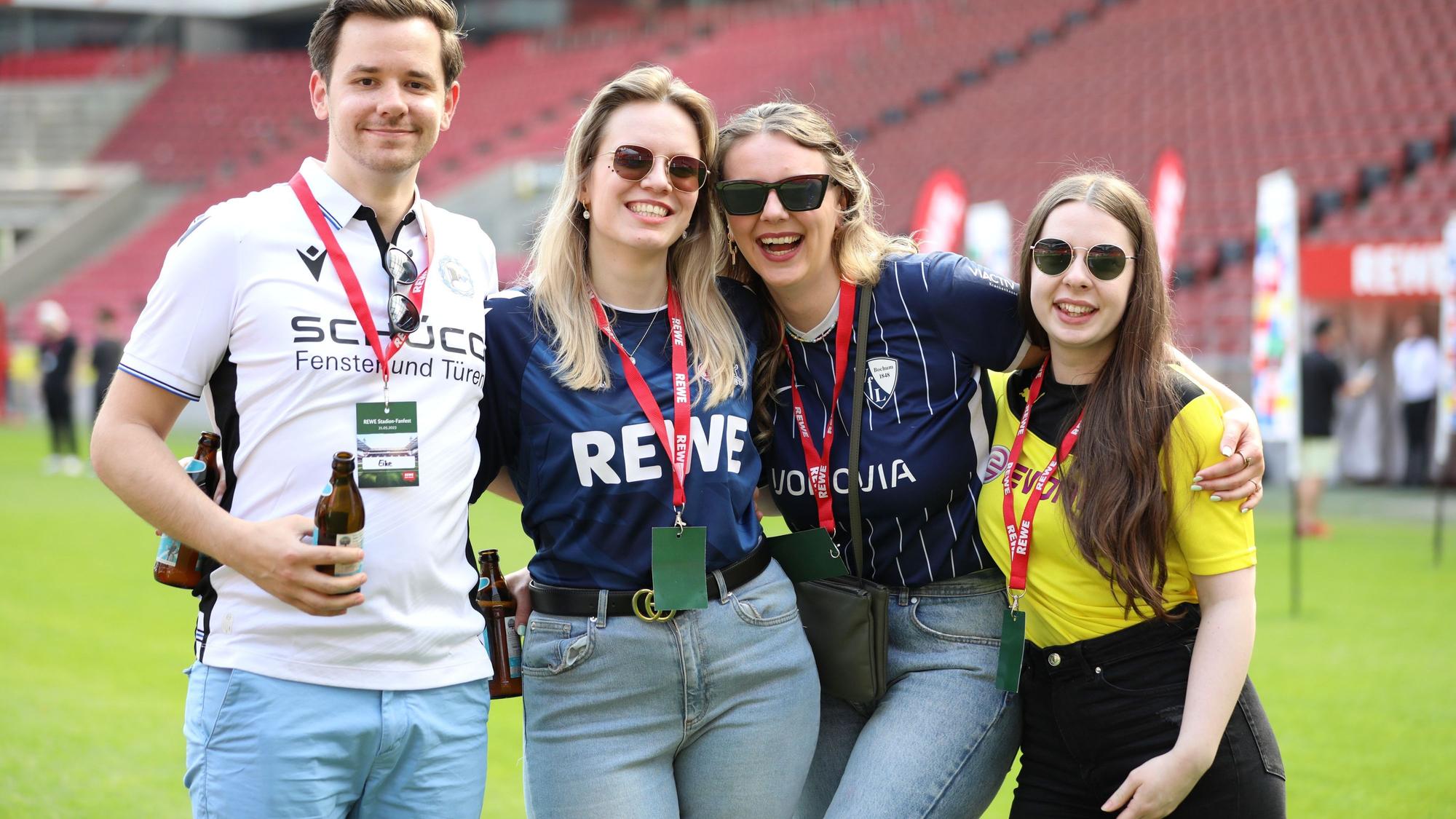 Drei Frauen und ein Mann stehen auf dem Rasen des Rhein-Energie-Stadions.