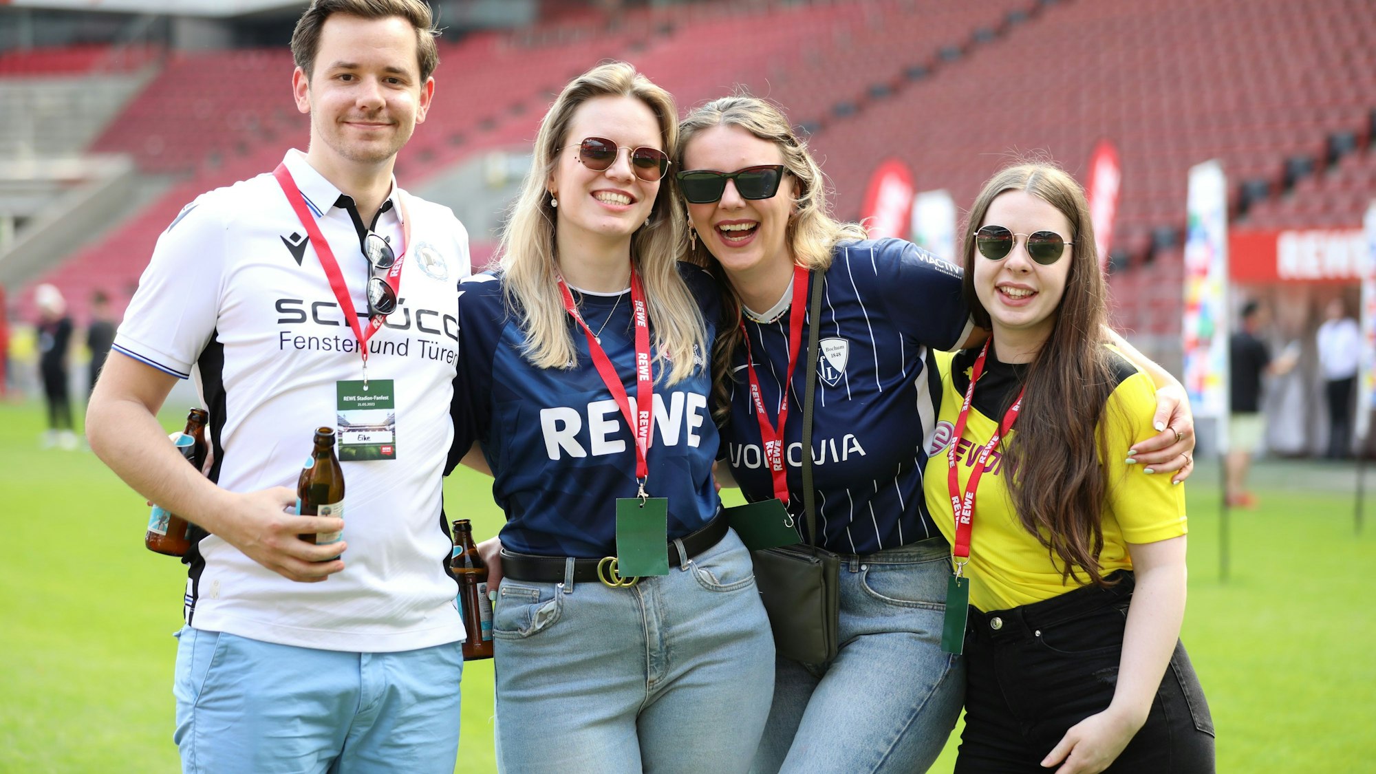 Drei Frauen und ein Mann stehen auf dem Rasen des Rhein-Energie-Stadions.