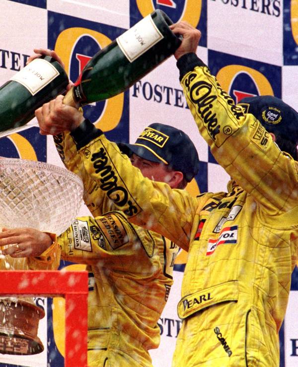 Eddie Jordan (l) genießt eine Sektdusche von seinen Fahrern Damon Hill (r) und Ralf Schumacher (M).