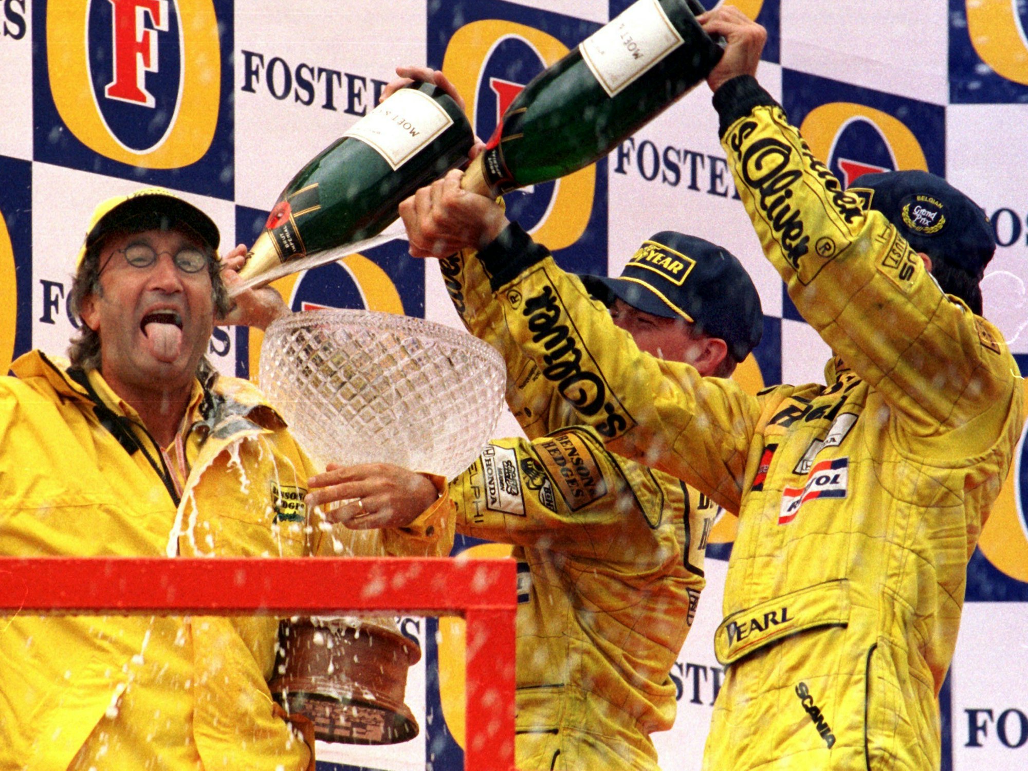 Eddie Jordan (l) genießt eine Sektdusche von seinen Fahrern Damon Hill (r) und Ralf Schumacher (M).