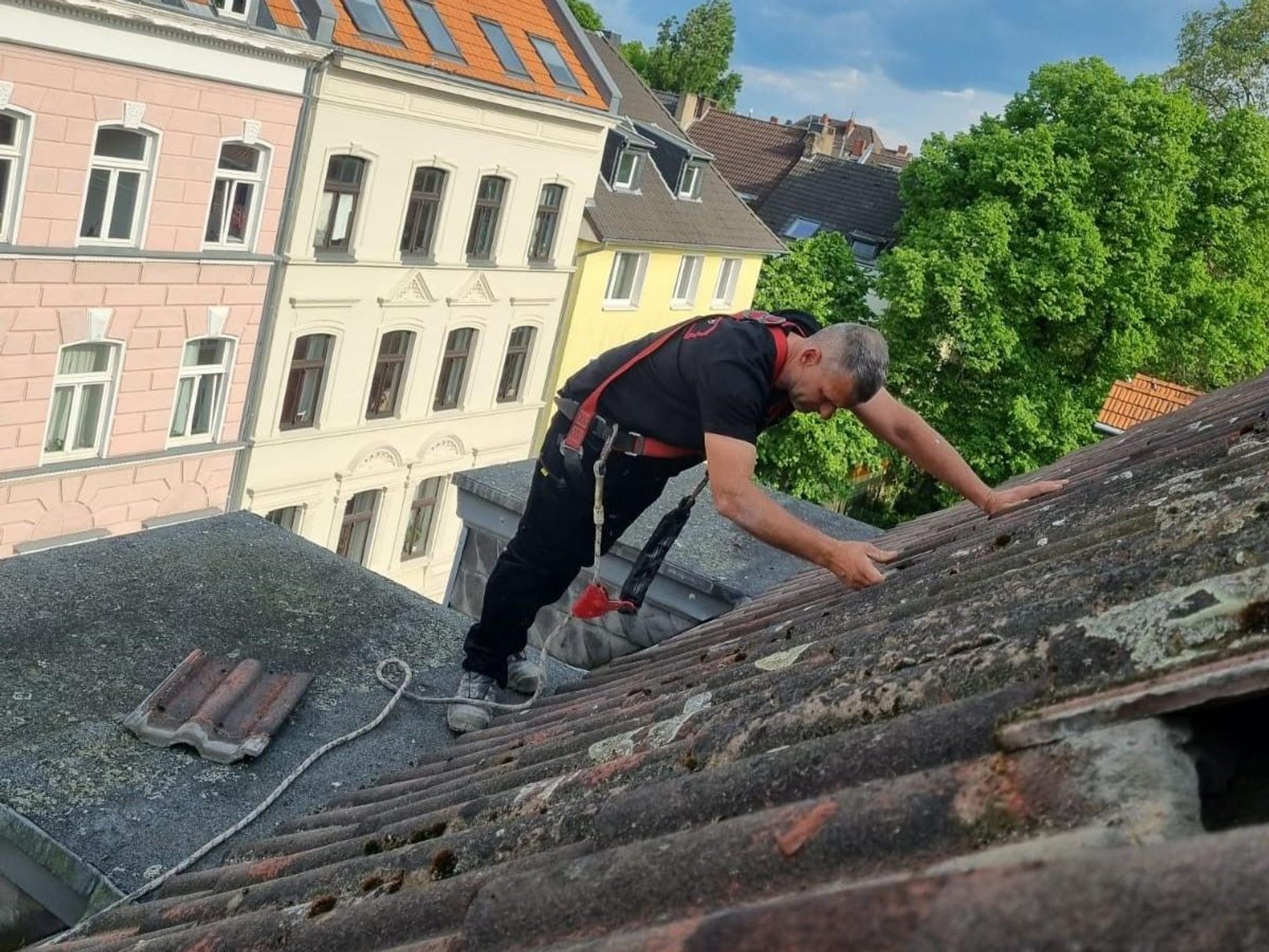 Ein Dachdecker deckt Ziegel ab.