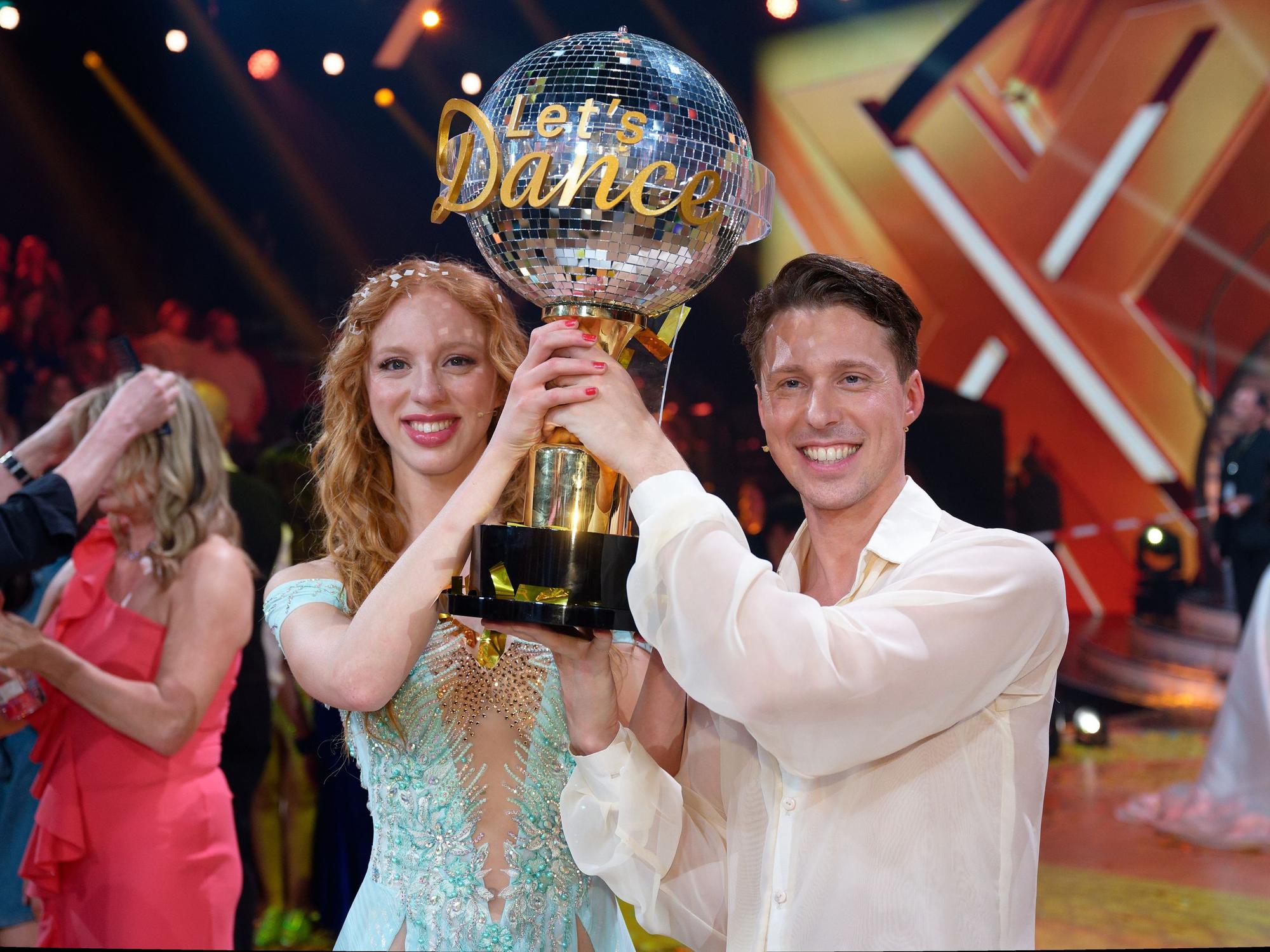 Model Anna Ermakova (l) und ihr Profi-Tanzpartner Valentin Lusin jubeln über ihren Sieg mit der Trophäe nach dem Finale der RTL Live-Tanzshow „Let's Dance“.