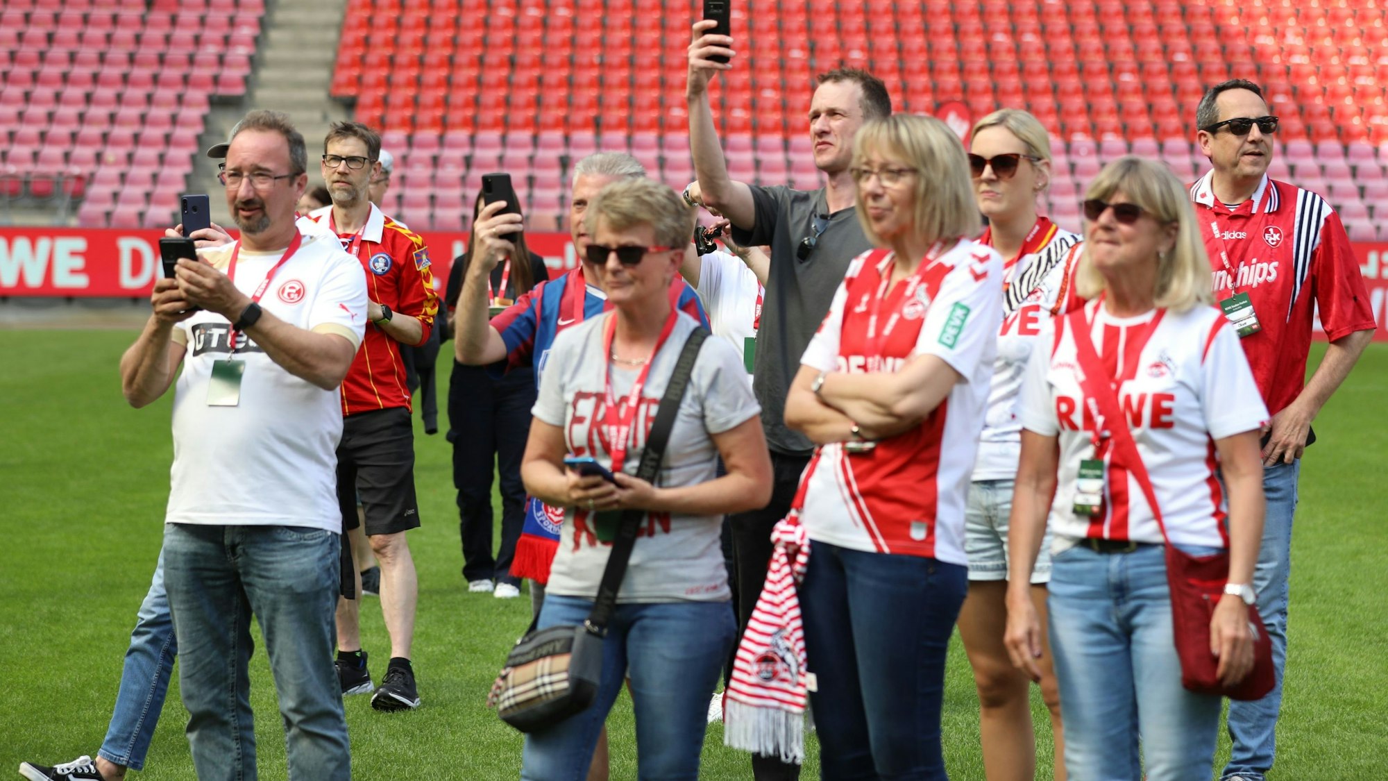 Fußballfans stehen auf dem Spielfeld, einige machen Fotos.