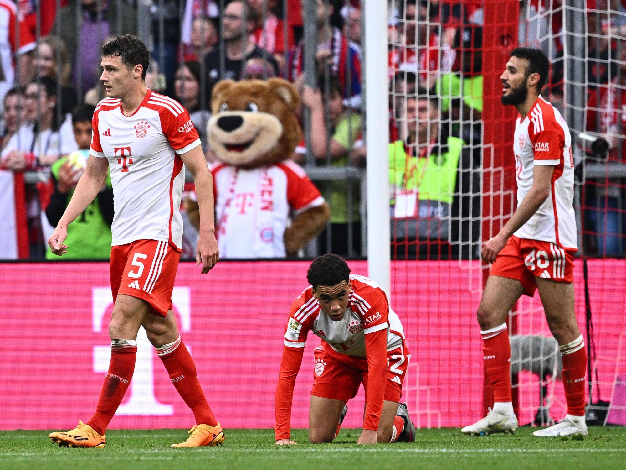 Münchens Benjamin Pavard, Jamal Musiala und Noussair Mazraoui gucken nach einem Gegentor ratlos. Musiala kniet auf dem Boden.