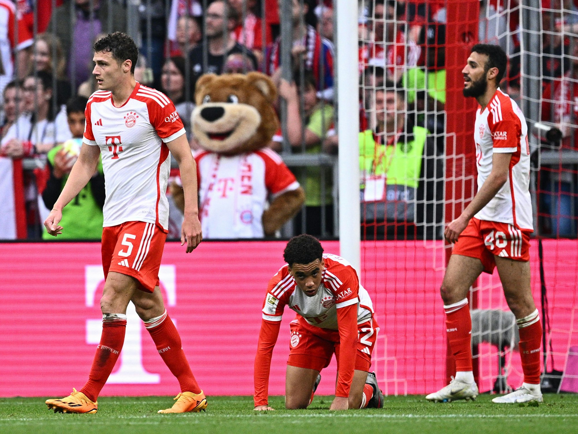 Münchens Benjamin Pavard, Jamal Musiala und Noussair Mazraoui gucken nach einem Gegentor ratlos. Musiala kniet auf dem Boden.