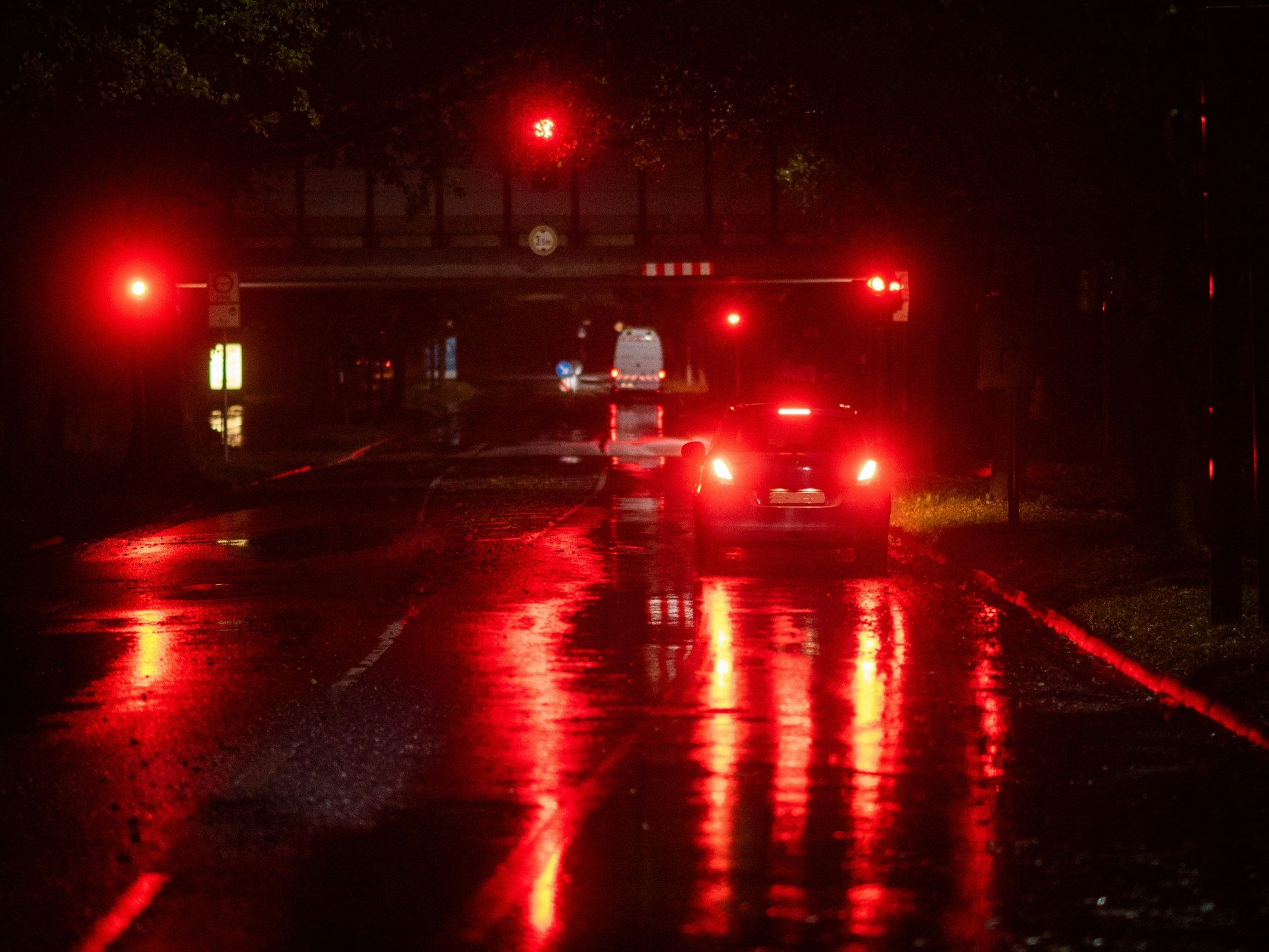 Ein Auto steht am frühen Morgen bei regnerischem Wetter an einer roten Ampel.