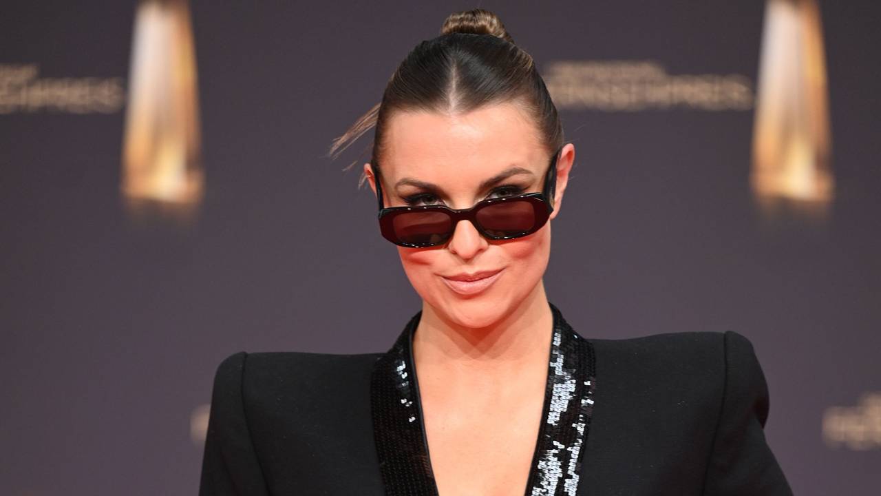 Laura Wontorra posiert auf dem roten Teppich für die Kameras. Sie trägt ein schwarzes Kleid und eine Sonnenbrille.