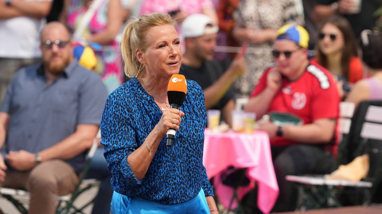 „Fernsehgarten“-Moderatorin Andrea steht im „Fernsehgarten“. Sie trägt ein blaues Oberteil und eine blaue Hose.