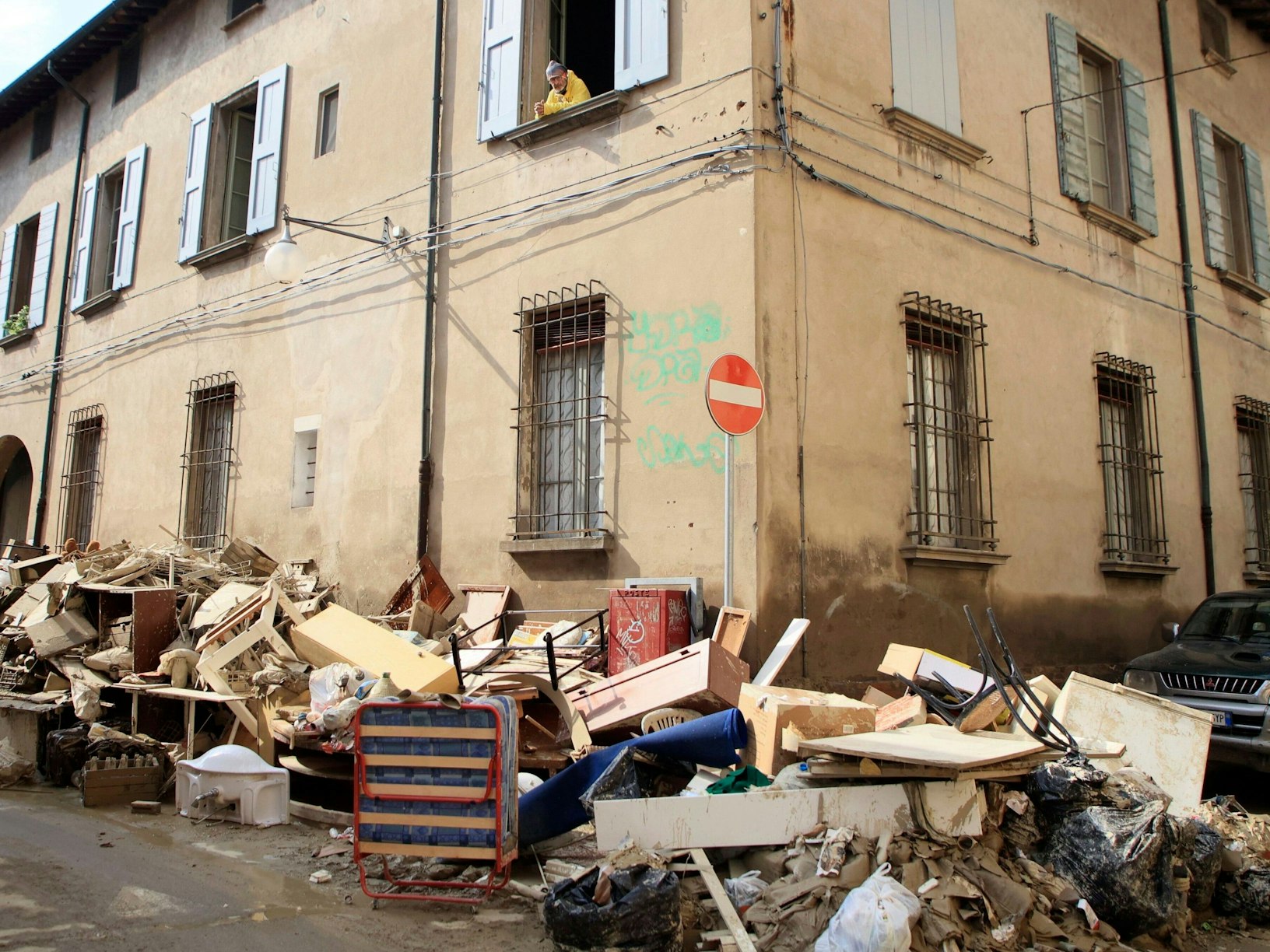 Ein Mann schaut aus einem Fenster auf Berge voller Haushaltsgegenstände, die durch die schweren Überschwemmungen beschädigt wurden.