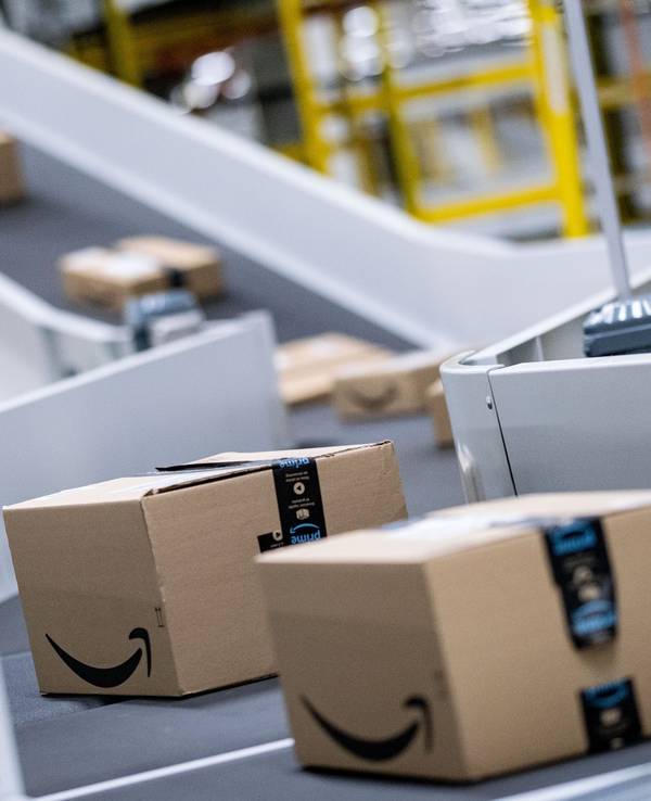 Pakete des Paketversenders Amazon laufen im Sortierzentrum über die Bänder.