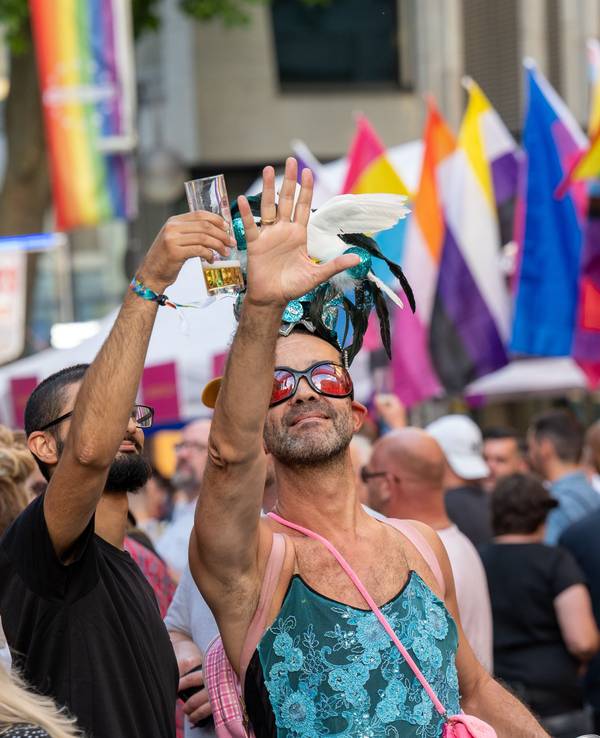 Zwei Männer halten den rechten Arm hoch, einer hält ein Kölschglas, der andere eine Taube.