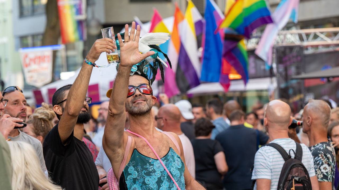 Zwei Männer halten den rechten Arm hoch, einer hält ein Kölschglas, der andere eine Taube.