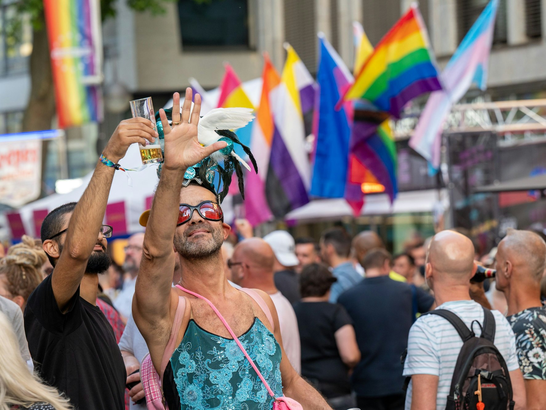 Zwei Männer halten den rechten Arm hoch, einer hält ein Kölschglas, der andere eine Taube.