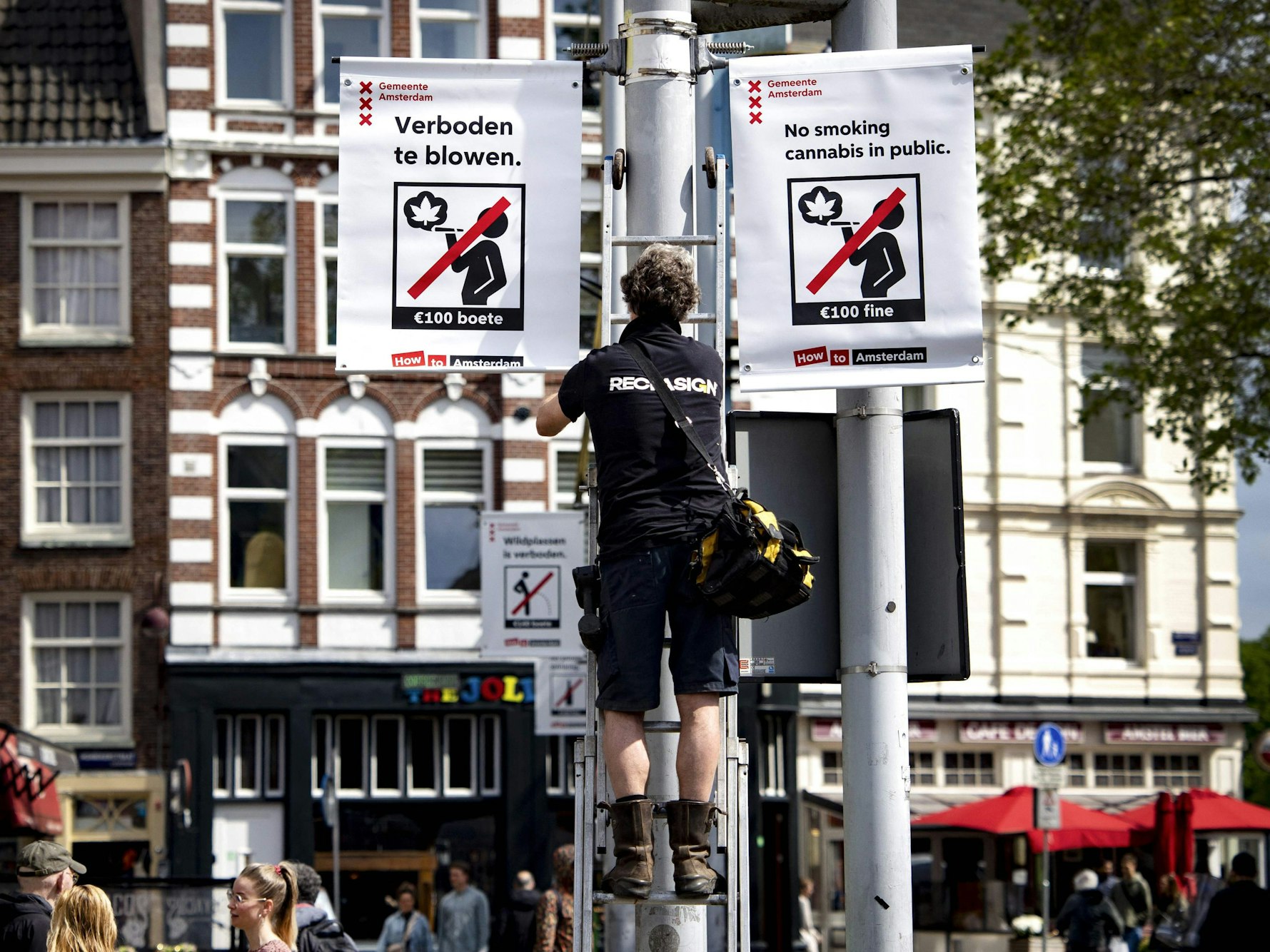 Ein Mitarbeiter der Stadt Amsterdam hängt ein Cannabis-Verbotsschild auf.
