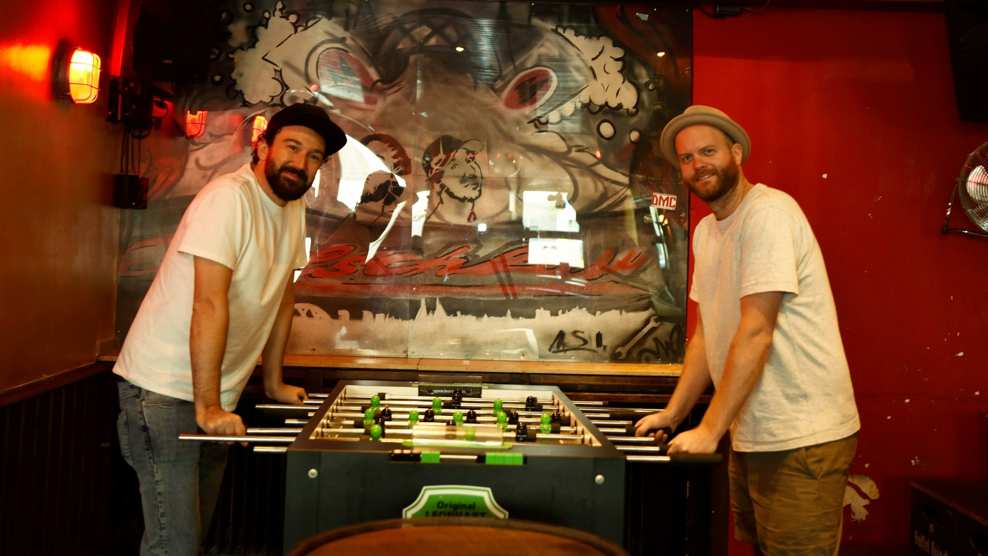 Die Wirte Dennis (r.) und Malte von der Kölschbar stehen an einem Tischkicker.