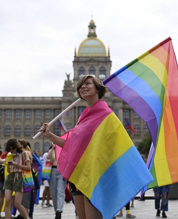 Eine Person trägt eine Regenbogenfahne und eine Pride-Fahne der Pansexuellen auf dem Prager Pride-Festival.