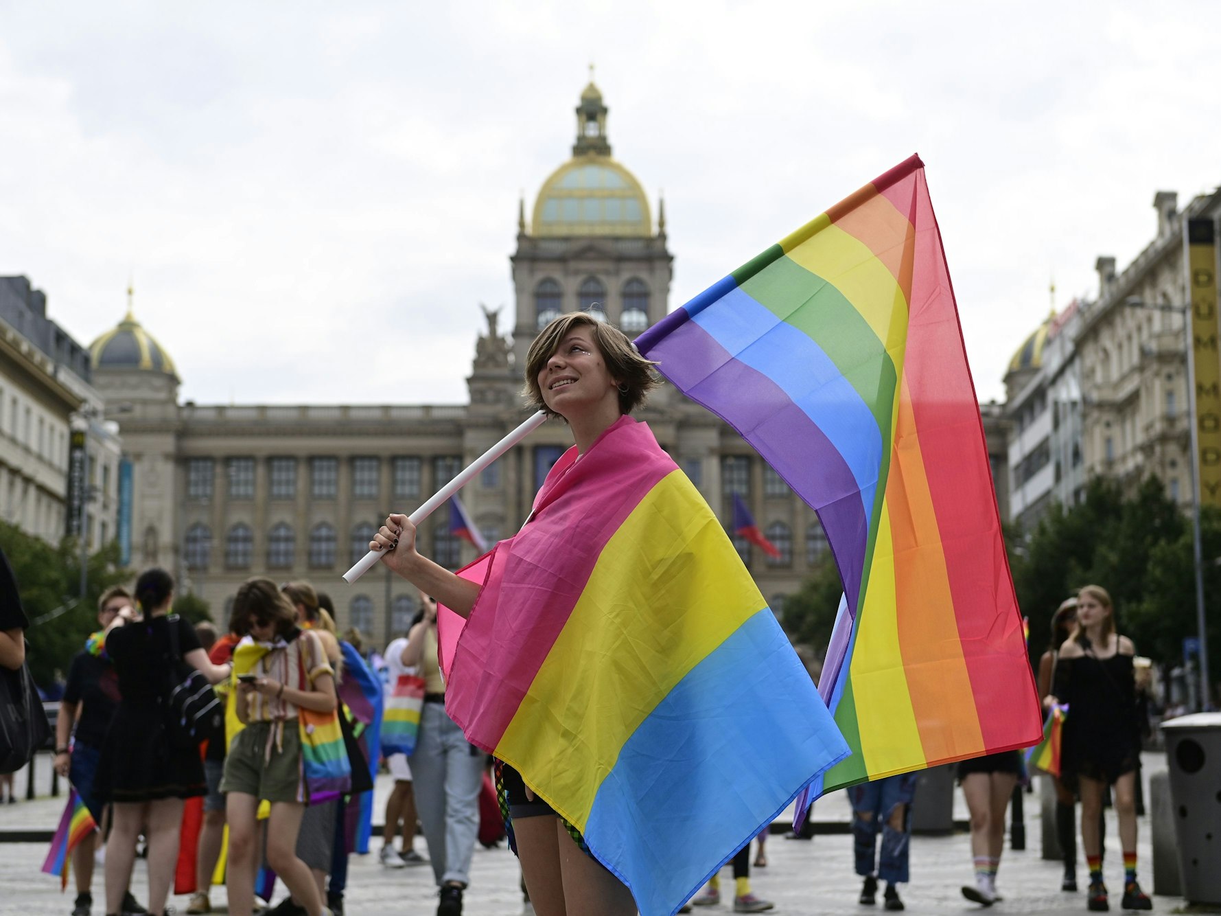 Eine Person trägt eine Regenbogenfahne und eine Pride-Fahne der Pansexuellen auf dem Prager Pride-Festival.