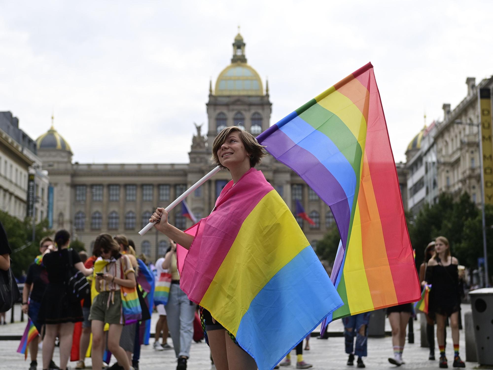 Eine Person trägt eine Regenbogenfahne und eine Pride-Fahne der Pansexuellen auf dem Prager Pride-Festival.