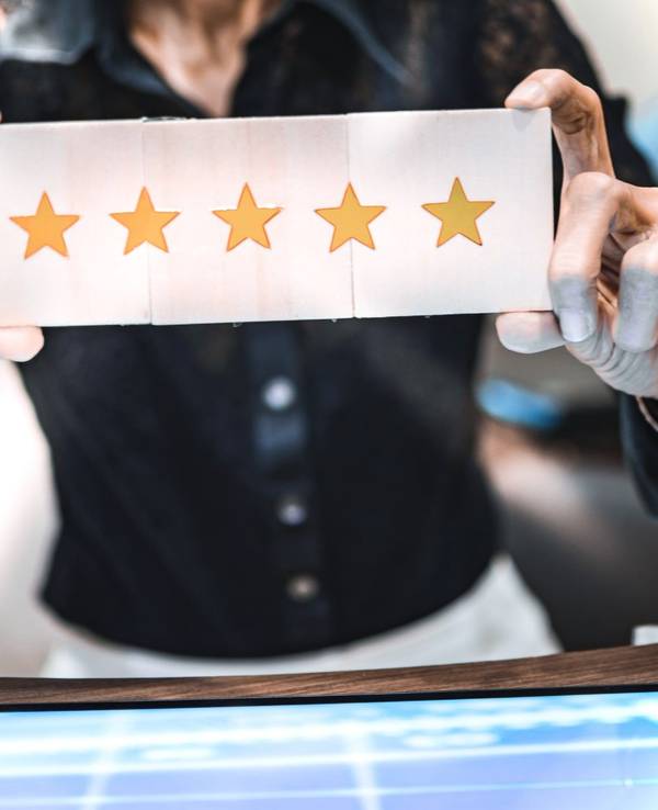 Frau hält Schild mit 5-Sternebewertung hoch.