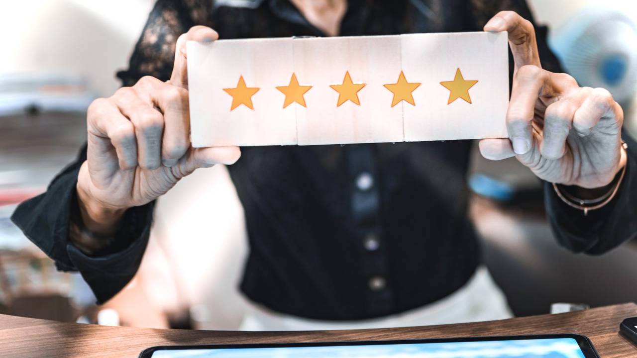 Frau hält Schild mit 5-Sternebewertung hoch.