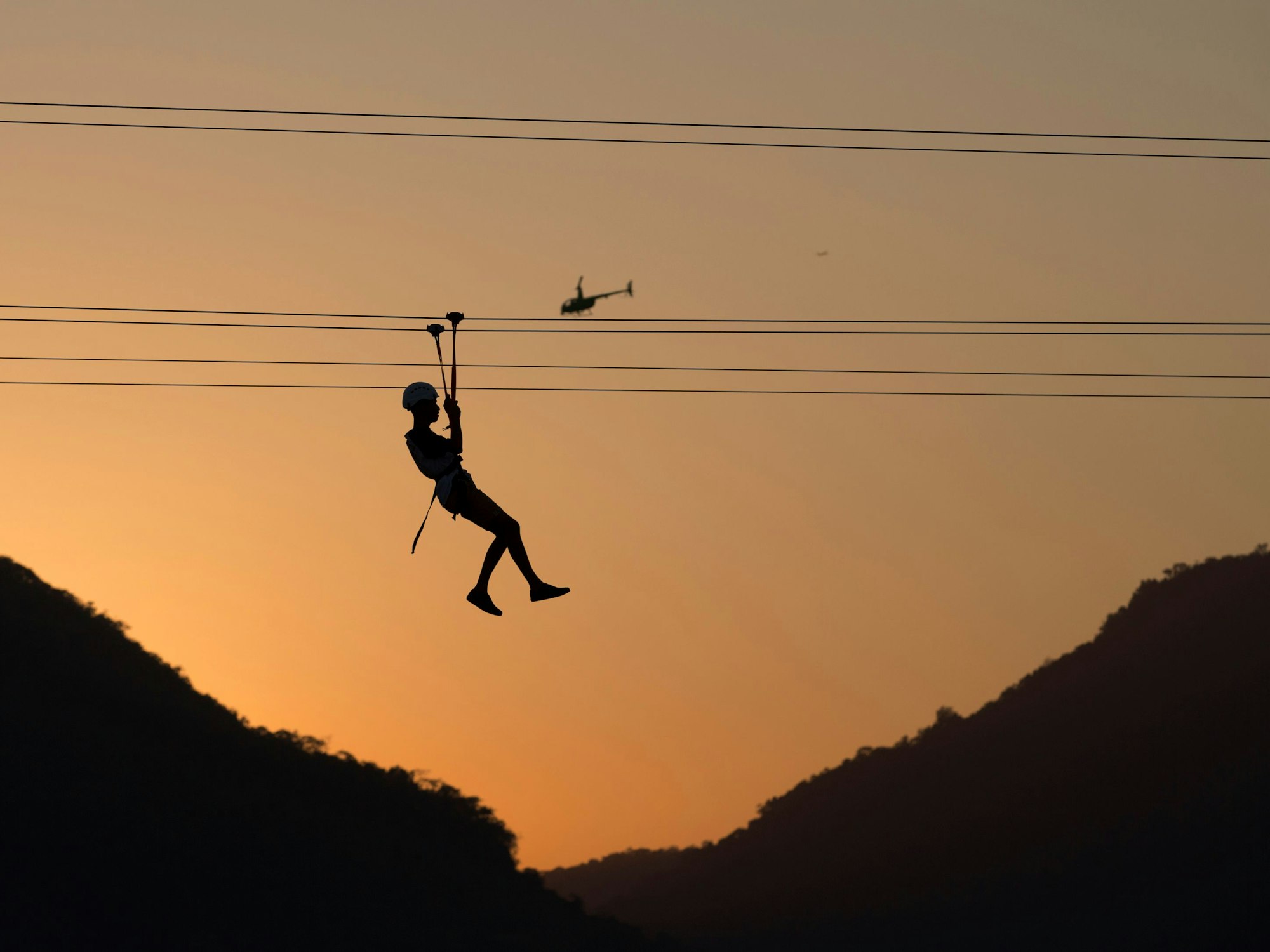 Ein Mann fährt in Rio de Janeiro (Brasilien) auf einer Seilrutsche.
