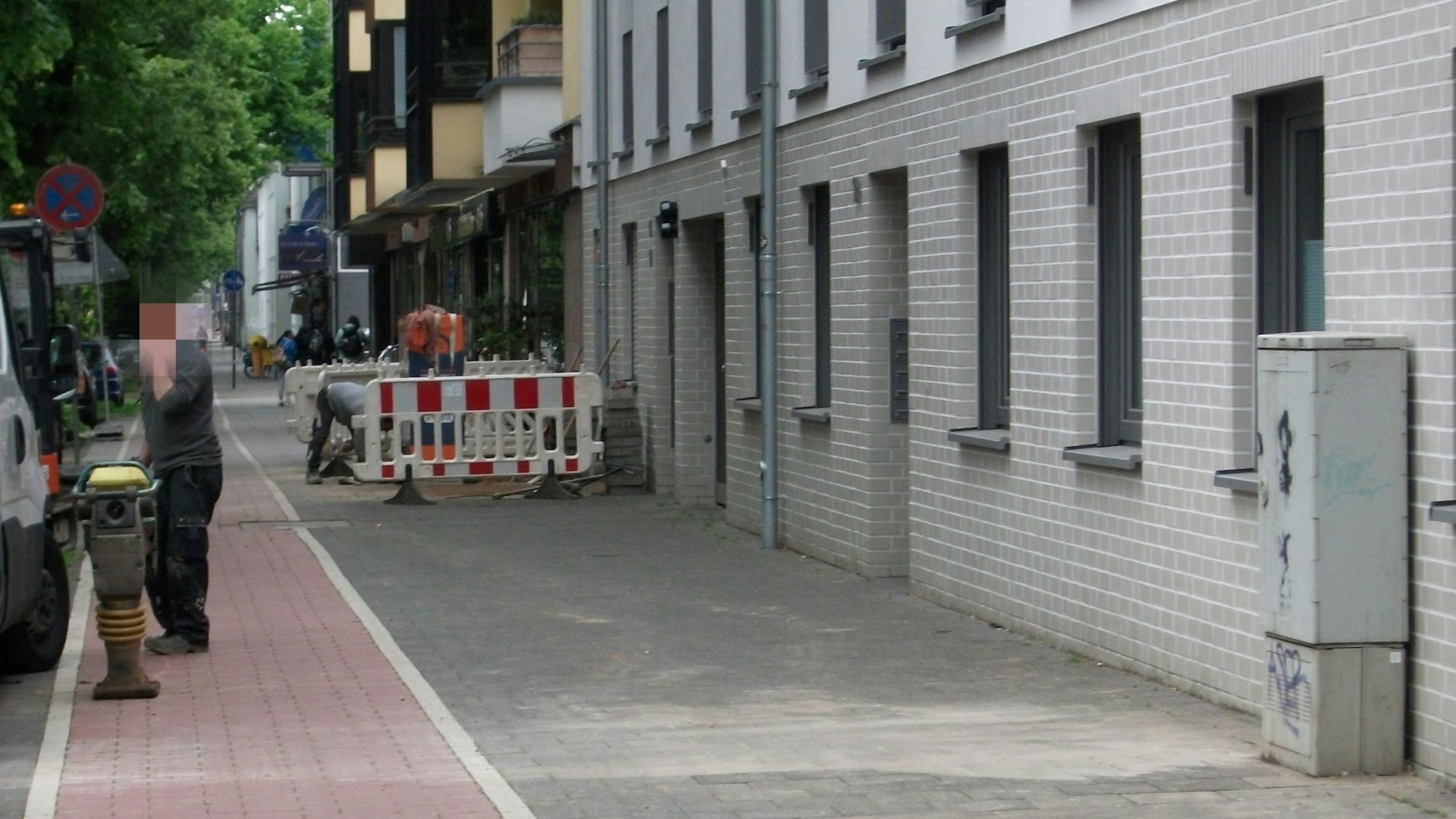 Ein Stromkasten wurde an die Hauswand versetzt. Ein paar Meter weiter finden Arbeiten an einem zweiten Stromkasten, der noch mitten auf dem Gehweg steht, statt.