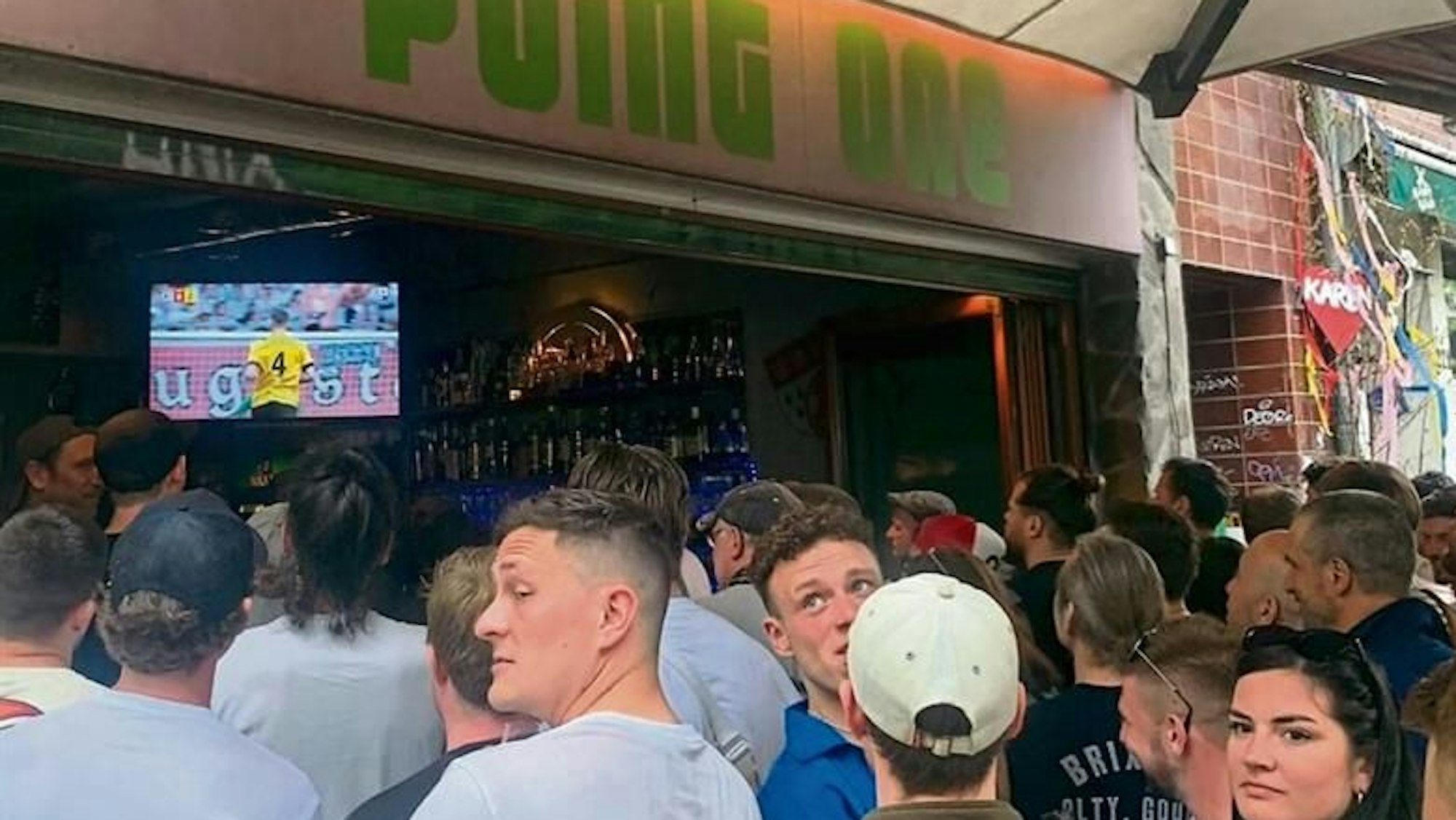 Menschen schauen in der Kölner Kneipe Point One das BVB-Spiel gegen Augsburg.