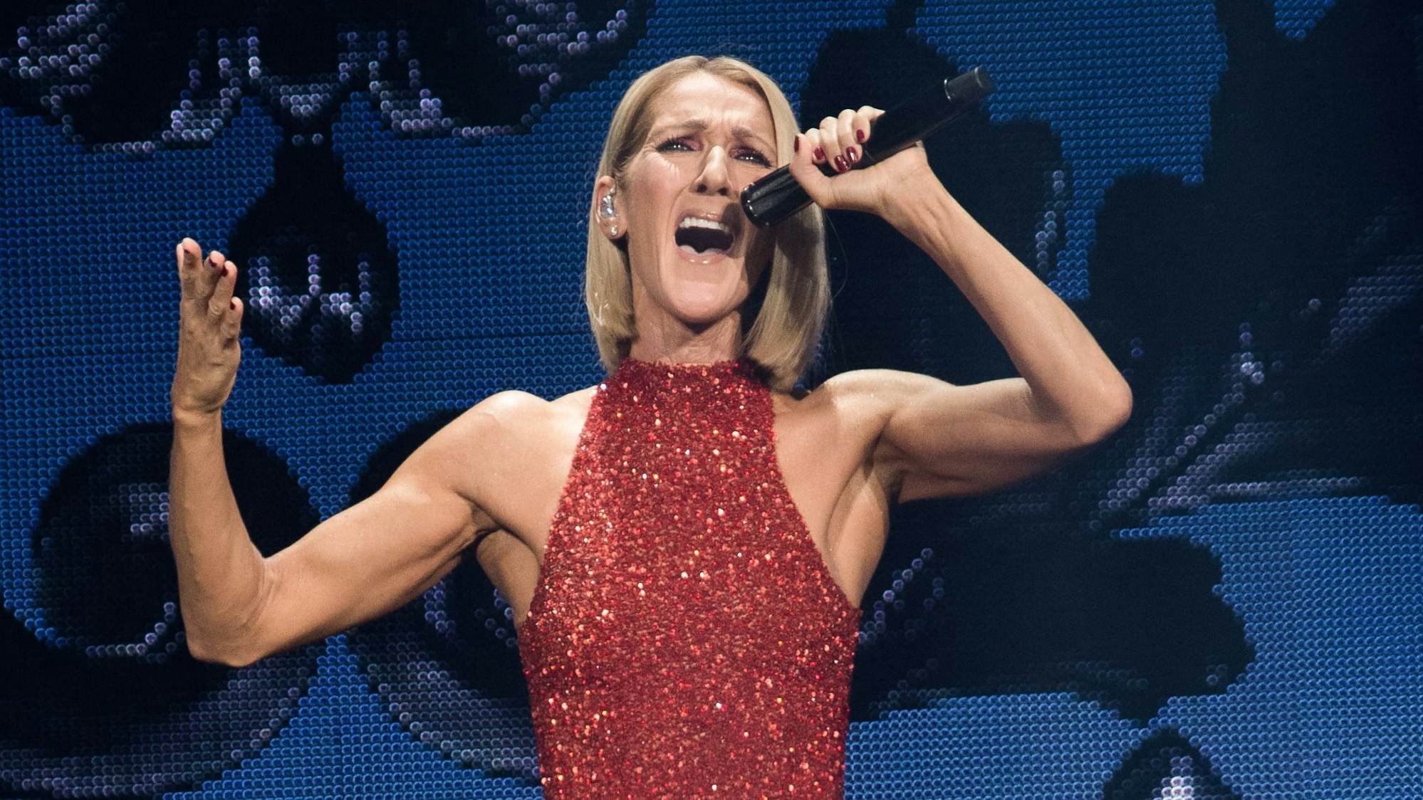 Sängerin Celine Dion singt im roten Glitzerkleid und mit Mikrofon in der Hand.