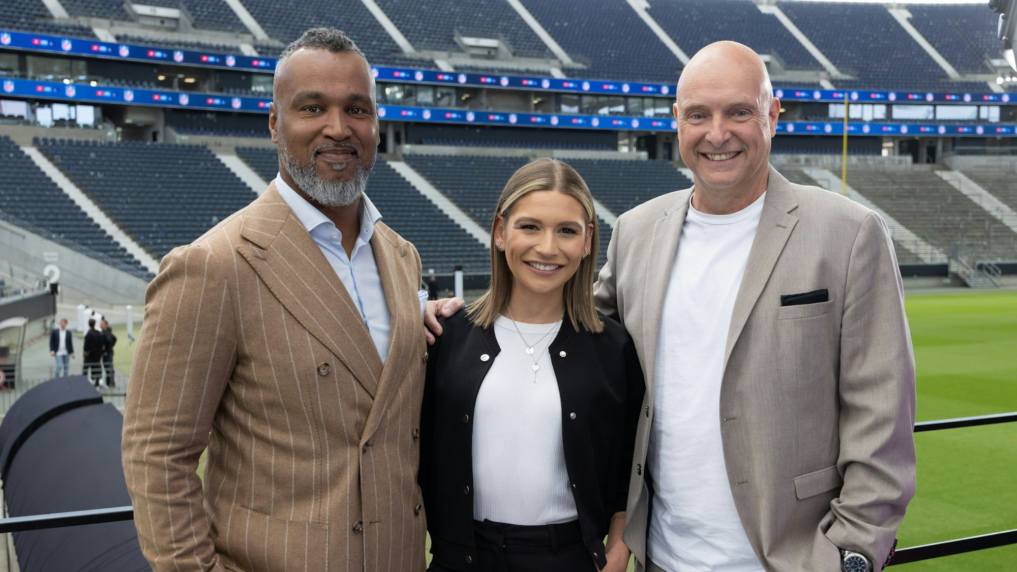 Frank Buschmann posiert mit Jana Wosnitza und Patrick Esume für ein Foto im Frankfurter Stadion.