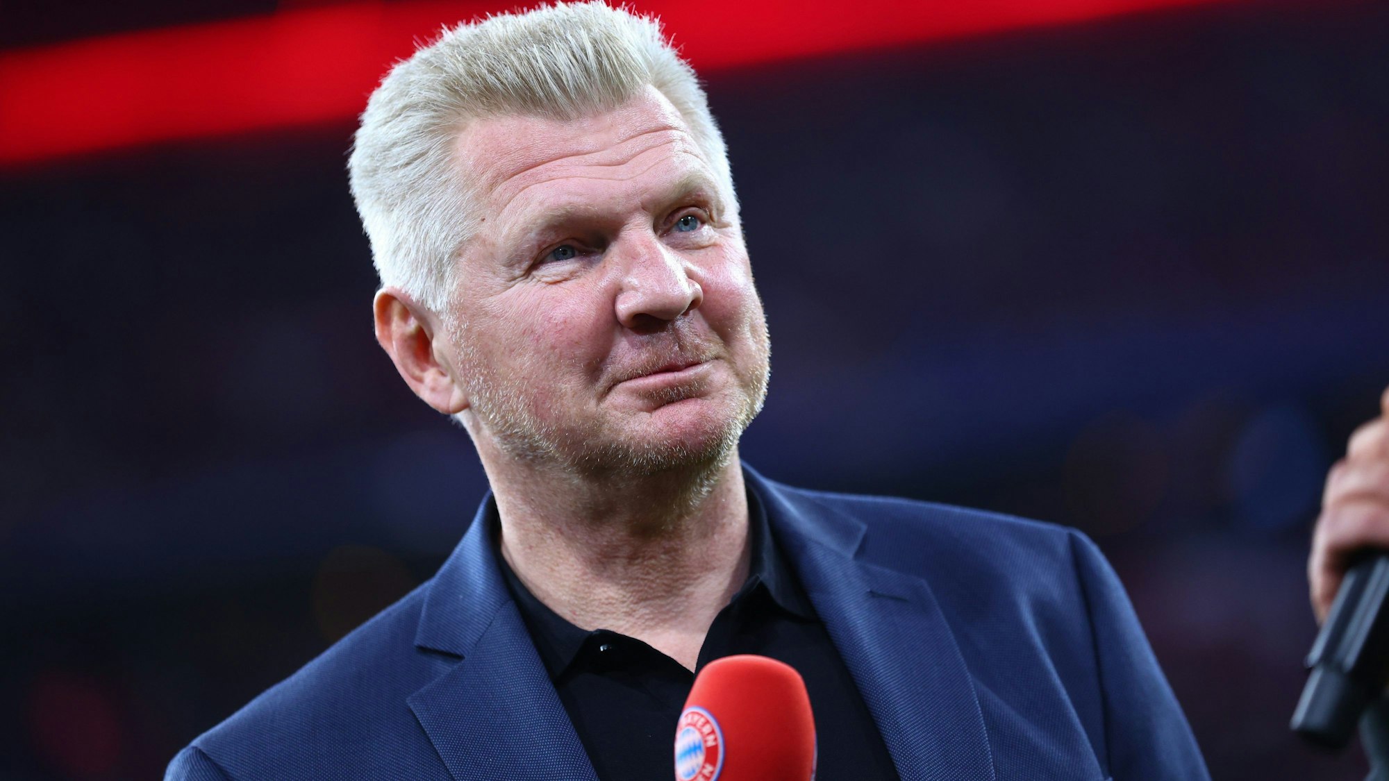 Stefan Effenberg hat ein Mikrofon in der Hand.