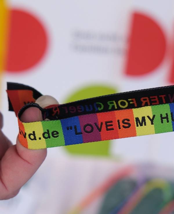 Ein Armband in Regenbogenfarben und schwarzer Schrift