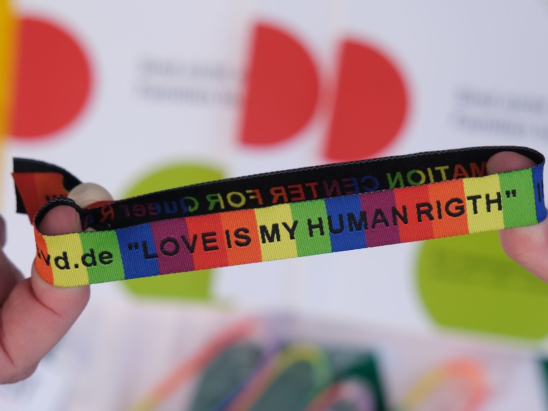 Ein Armband in Regenbogenfarben und schwarzer Schrift