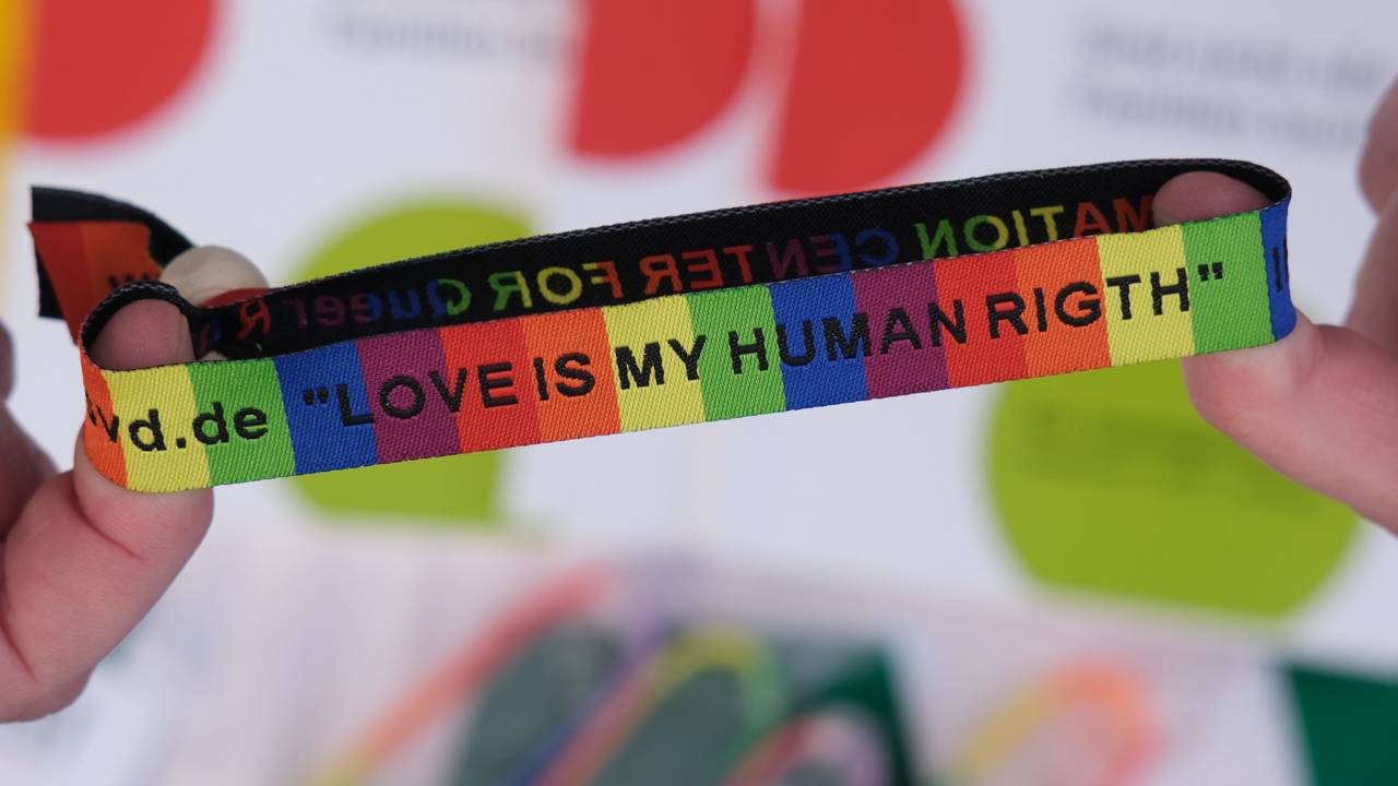 Ein Armband in Regenbogenfarben und schwarzer Schrift