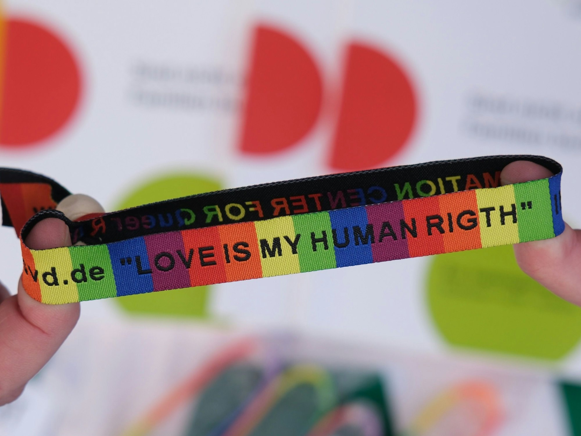 Ein Armband in Regenbogenfarben und schwarzer Schrift