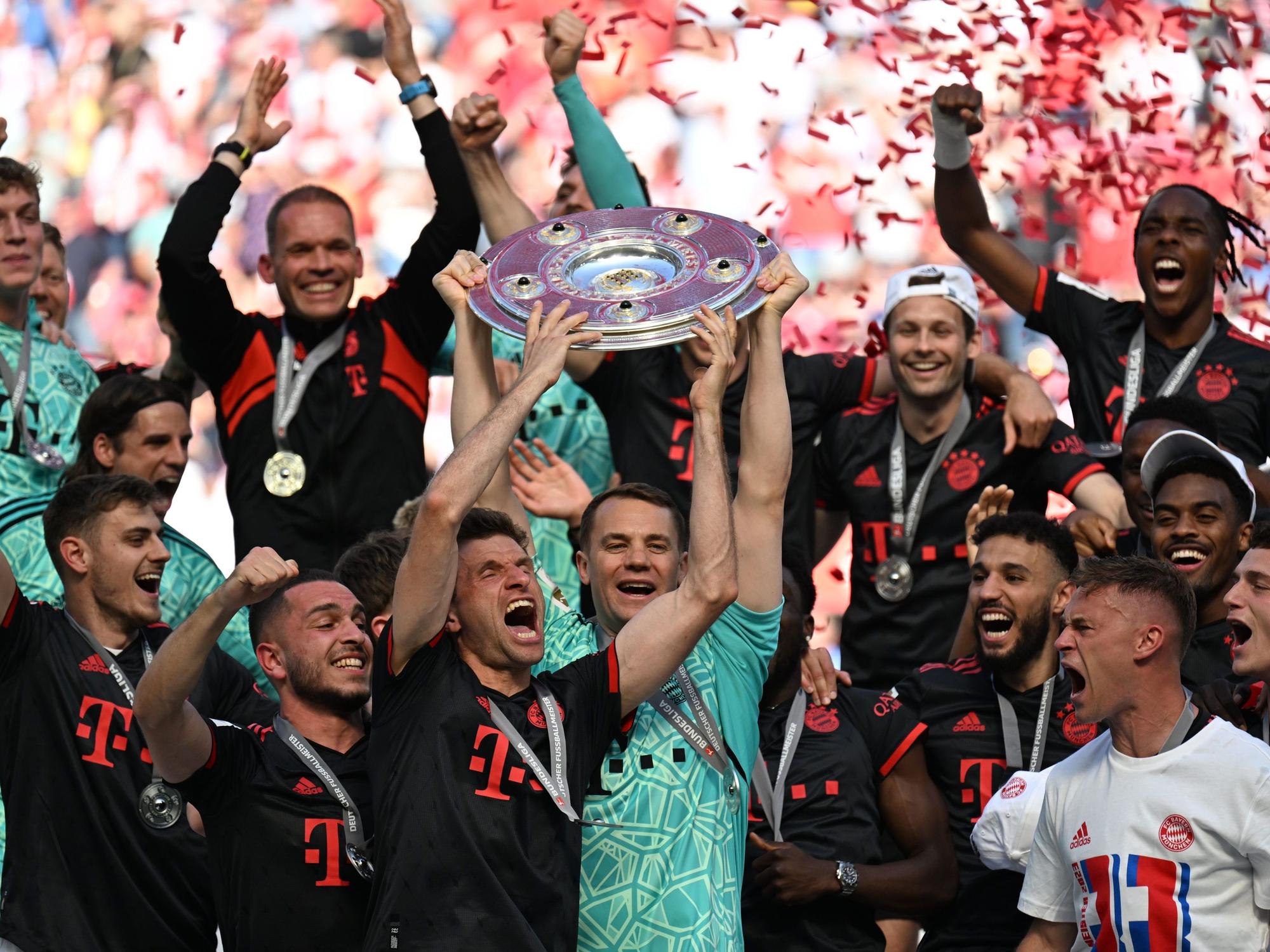 Bayerns Torhüter Manuel Neuer (M) hält die Meisterschale hoch.
