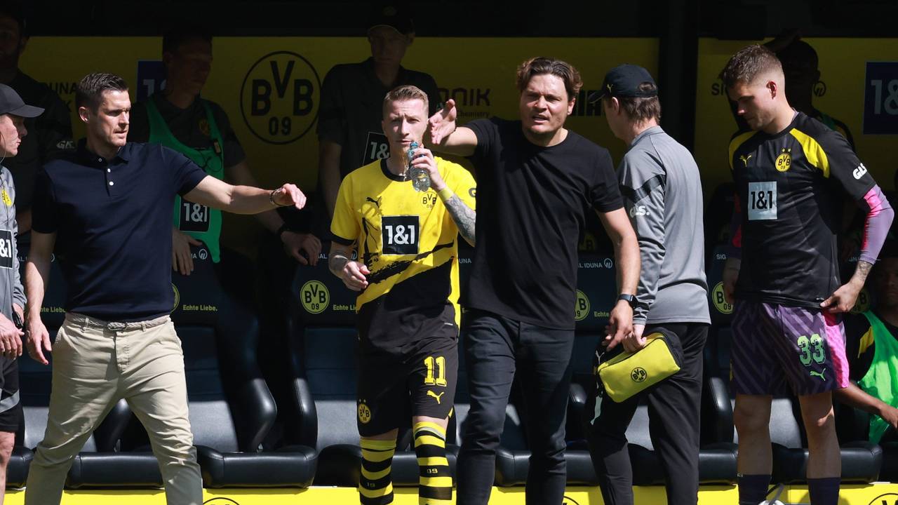 Sebastian Kehl, Marco Reus und Edin Terzic stehen an der Seitenlinie. Reus trinkt aus einer Wasserflasche, Kehl und Terzic gestikulieren.