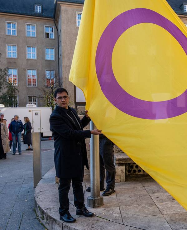Zwei Personen halten eine gelb-lila Flagge