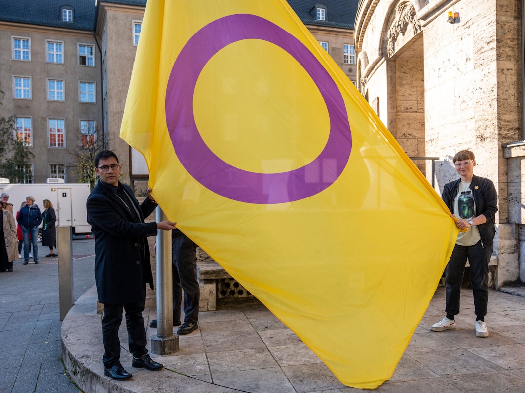 Zwei Personen halten eine gelb-lila Flagge