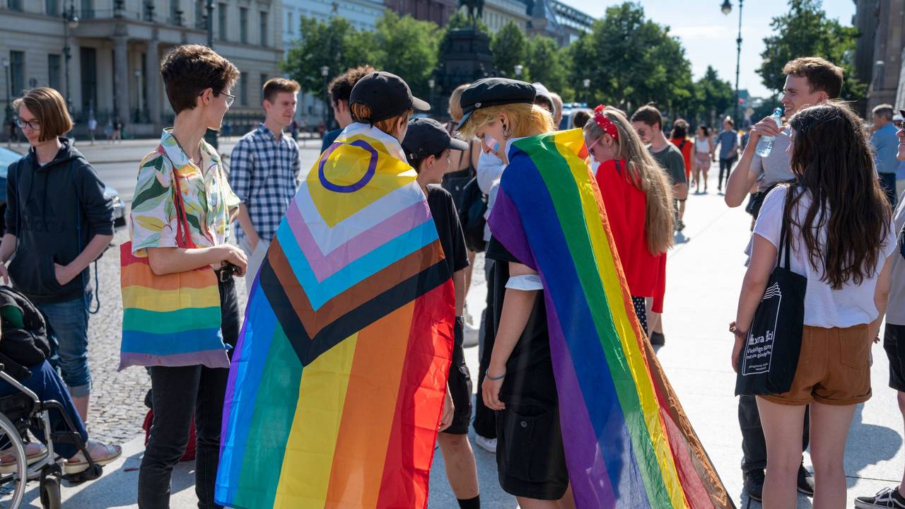 Mehrere Personen mit Regenbogenfahnen.