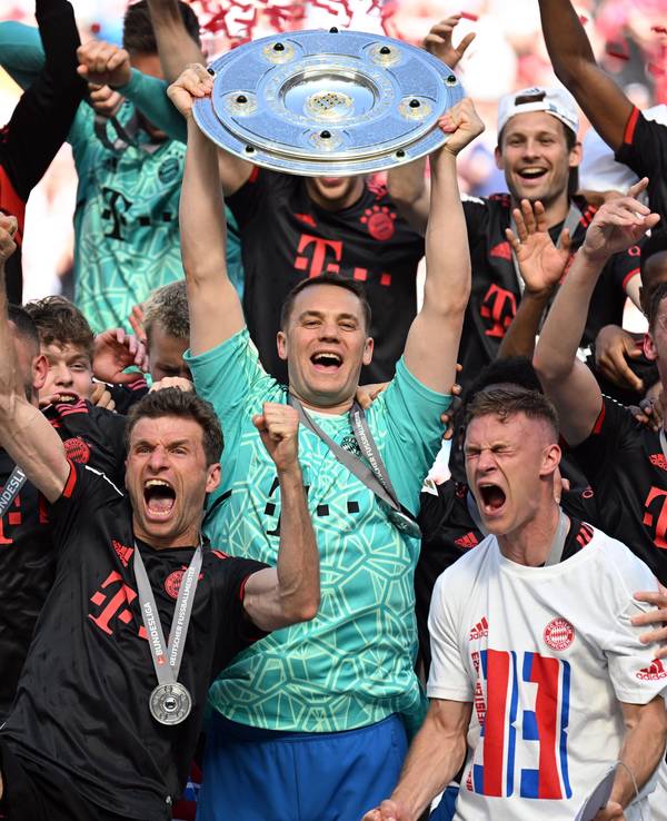 Bayerns Torhüter Manuel Neuer hält die Meisterschale, während seine Teamkollegen nach dem Gewinn der 33. deutschen Meisterschaft jubeln.