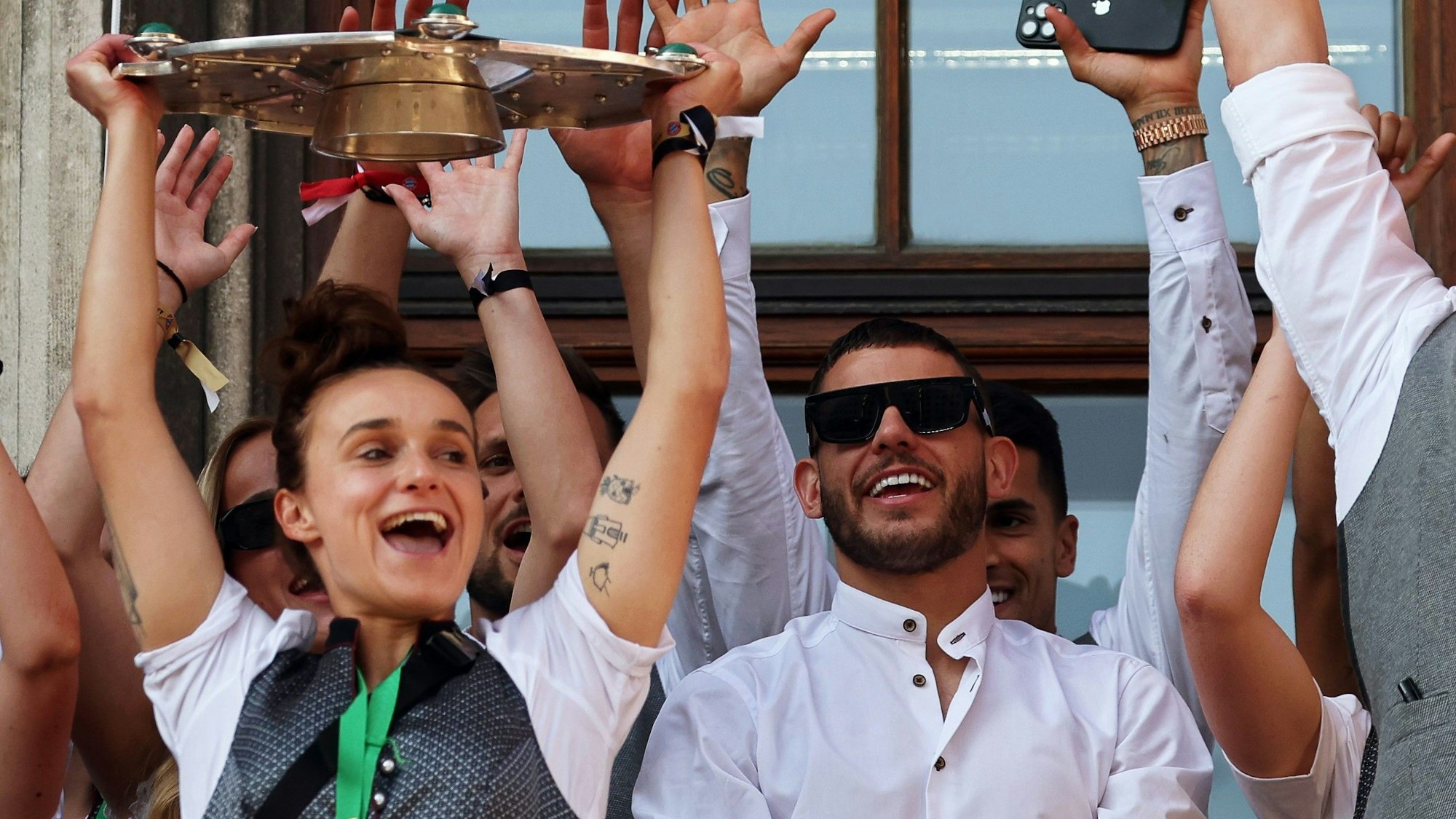 Lina Magull (l.) reckt die Meisterschale in die Höhe. Dabei ist auch ein Tattoo der Spielführerin der Frauen des FC Bayern München zu sehen.